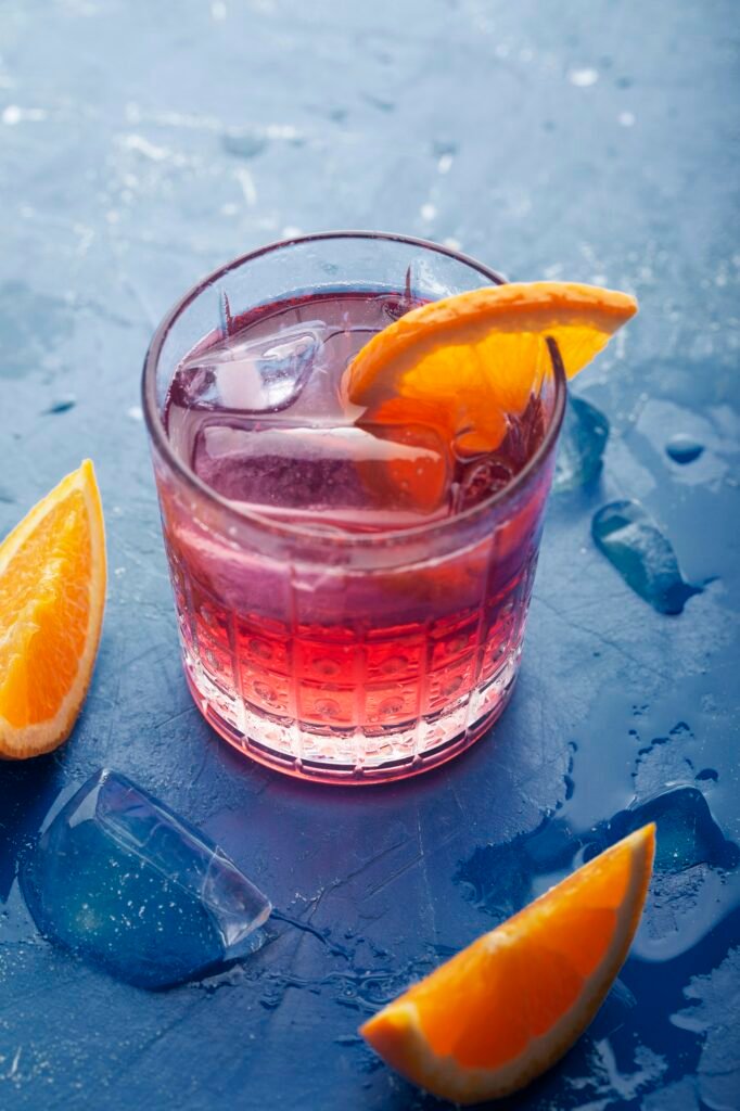 Fresh ice tea summer cocktail with orange and ice. Background toned in modern blue color 2020