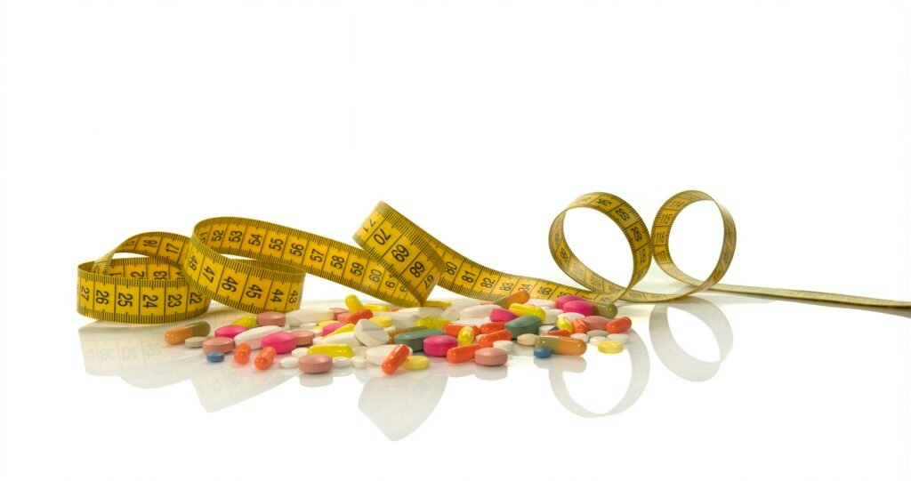 Tape measure and diet pills isolated on white background