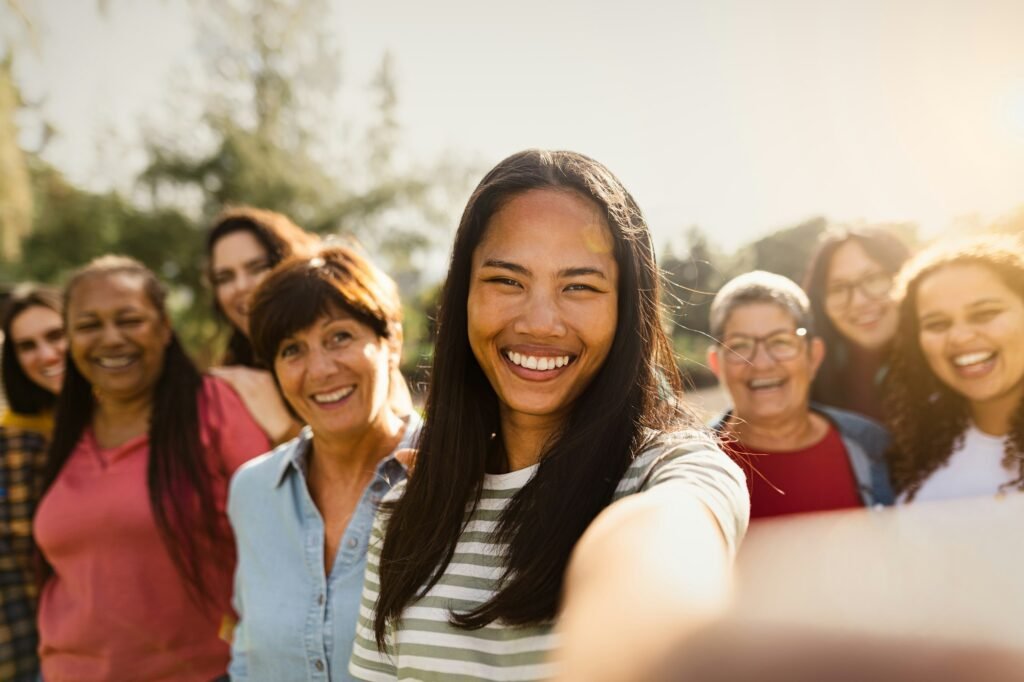 Happy multigenerational group of women having fun taking selfie with smartphone camera in a park