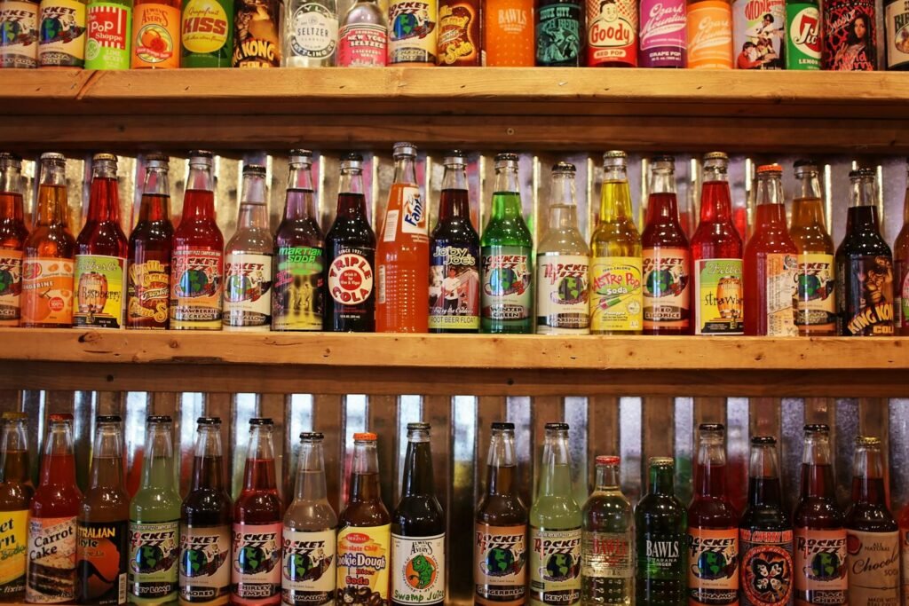 A vibrant collection of vintage soda bottles displayed on wooden shelves in a store.