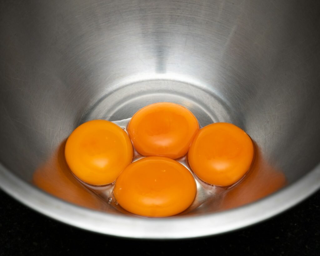 a metal bowl filled with four eggs on top of a counter
