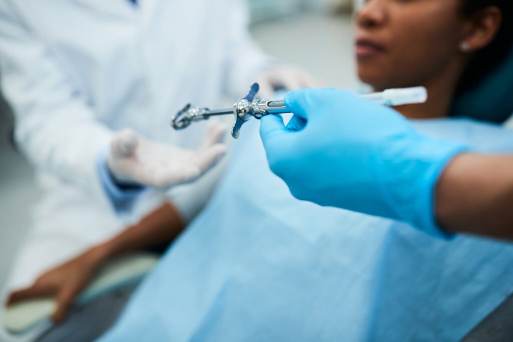 Close up of dental assistant passing syringe to a dentist during patient's dental procedure.