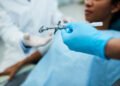 Close up of dental assistant passing syringe to a dentist during patient's dental procedure.
