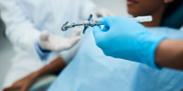 Close up of dental assistant passing syringe to a dentist during patient's dental procedure.