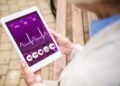 selective focus of senior woman holding digital tablet with heartbeat rate on screen