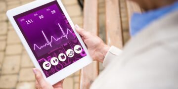 selective focus of senior woman holding digital tablet with heartbeat rate on screen