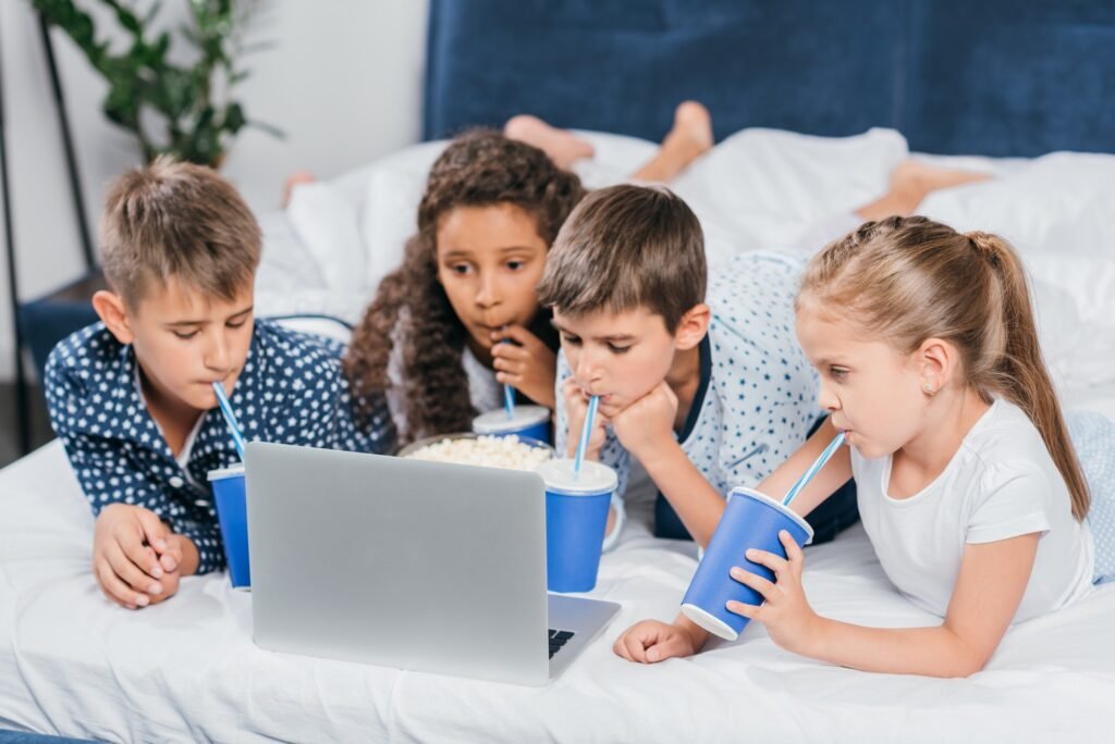 multicultural children drinking soda and watching movie at home together