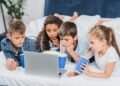 multicultural children drinking soda and watching movie at home together