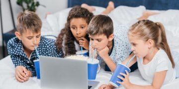 multicultural children drinking soda and watching movie at home together