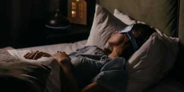 A woman peacefully sleeping with an eye mask in a dimly lit bedroom, capturing a serene bedtime atmosphere.